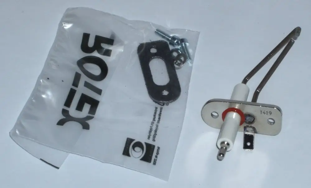 Daikin Zündelektrode in Verpackung, zusammen mit einer Dichtung und Schrauben, dargestellt auf weißem Hintergrund.